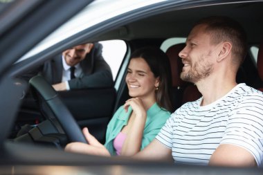 Satış elemanı mutlu aileye yeni araba gösteriyor, seçici odaklanma