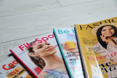 Beyaz ahşap masada farklı moda dergiler, yakın plan. Metin için boşluk