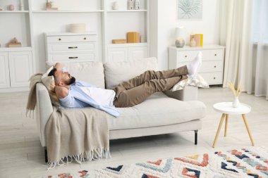 Uyum. Evdeki rahat koltukta dinlenen bir adam.