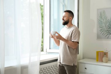 Uyum. Evinin penceresinin yanında bir bardak içkisi olan adam.