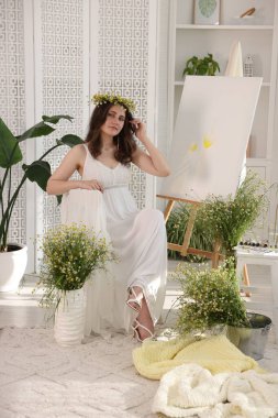 Papatya çelengi olan güzel bir kadın kapalı alanda sehpanın yanında.