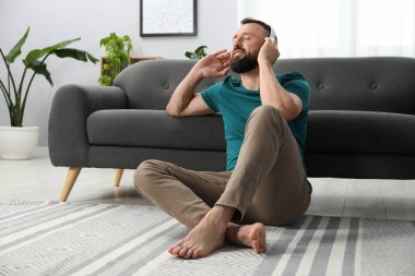 Uyum. Evde kulaklıkla müzik dinleyen bir adam.