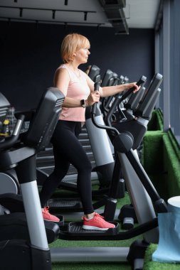 Son sınıf kadın spor salonunda eliptik makine eğitimi alıyor.