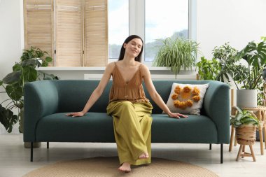 Uyum. Gülümseyen kadın evdeki kanepede dinleniyor.