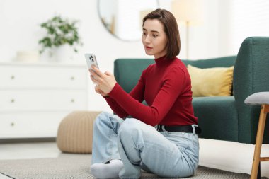 Evde modern akıllı telefon kullanan bir kadın.