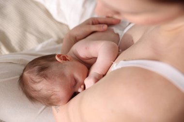 Anne yeni doğmuş bebeğini evin içinde emziriyor.