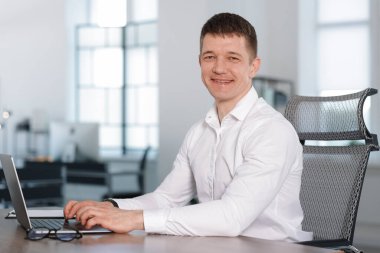 Ofisteki masada dizüstü bilgisayarda çalışan bir adam. Metin için boşluk