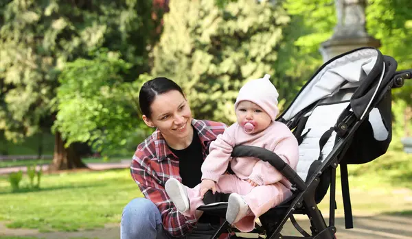 Parkta bebek arabasında sevimli bebeğiyle annesi