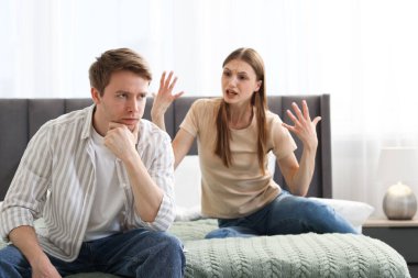 Kadın ve erkek evde yatakta kavga ediyorlar.