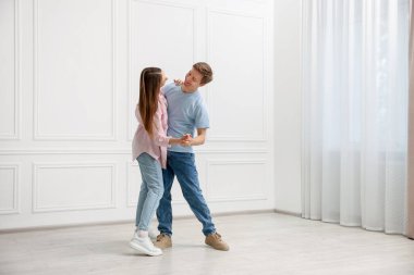 Mutlu çift evde beyaz duvarın yanında dans ediyor.