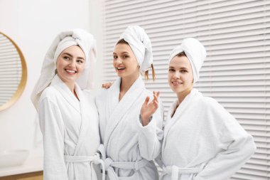 Kapalı alanda yapılan spa ameliyatlarından sonra bornozlu mutlu kadınlar.