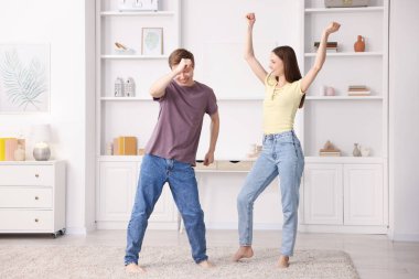 Mutlu genç çift evde dans ediyor.