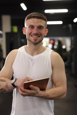 Spor merkezinde tableti olan kişisel antrenör.