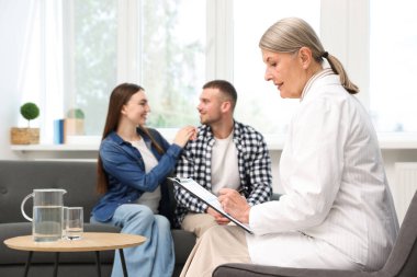 Tüp bebek (tüp bebek). Üreme kliniğinde doktorla görüşen çift, seçici odaklanma