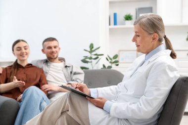 Tüp bebek (tüp bebek). Üreme kliniğinde doktorla görüşen çift, seçici odaklanma