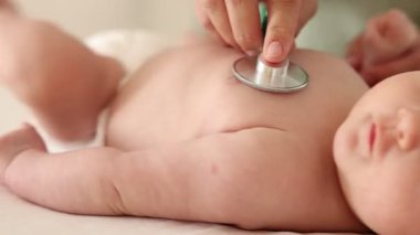 Doktor hastanede steteskopla şirin bebeği muayene ediyor.