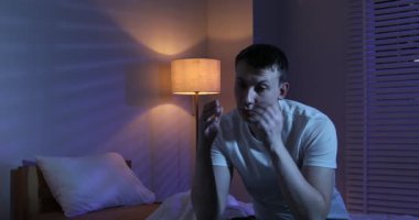 Evde yatağında uykusuzluk çeken, hayal kırıklığına uğramış bir adam, kamera aşağı iniyor.