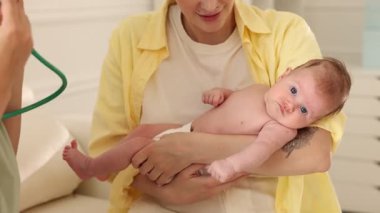 Anne ve sevimli küçük çocuğunun hastanede çocuk doktoruyla randevusu var. Doktor steteskopla bebeği muayene ediyor.