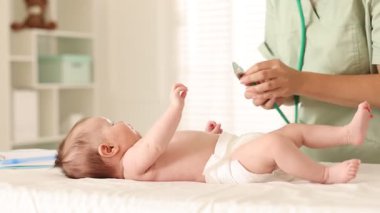 Doktor hastanede steteskopla şirin bebeği muayene ediyor.