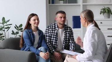 Tüp bebek (tüp bebek). Mutlu çift, üreme kliniğindeki doktorla randevusu sırasında sarılıyor.