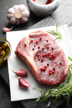 Siyah masanın üstünde çiğ et ve baharat var.