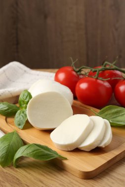 Lezzetli mozzarella, domates ve fesleğen ahşap masada, yakın plan.