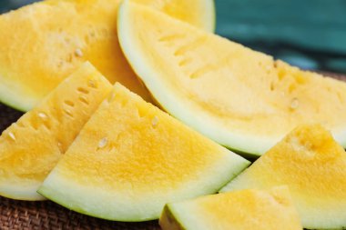 Olgun sarı karpuz parçaları hasır masada, yüzme havuzunun yanında, yakın plan.