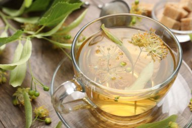 Taze ıhlamur çayı, şeker küpleri ve çiçekler ahşap masada, yakın plan.