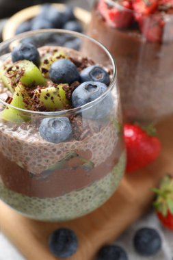 Chia tohumlu lezzetli çikolatalı puding, kivi ve yaban mersinli gri masada, yakın plan.