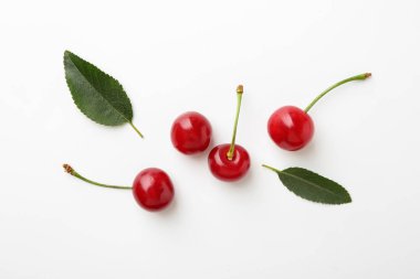 Beyaz arka planda taze kirazlar, düz uzanmış.