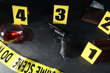 Adli tıp uzmanı. Sarı olay yeri bandı, siyah masanın üstünde işaretler ve kanıtlar var.