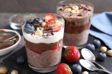 Chia tohumlu, fındıklı ve böğürtlenli lezzetli çikolatalı pudingler gri masada, yakın plan.