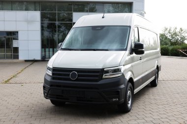 Asfalt yolda park etmiş beyaz bir minibüs.