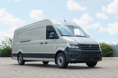 Asfalt yolda park etmiş beyaz bir minibüs.