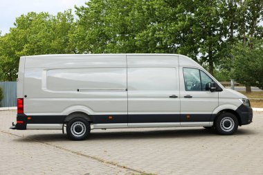 Asfalt yolda park etmiş beyaz bir minibüs.