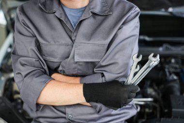 Otomobil parçaları. Kaputu açık, kapalı kaputun yanında farklı anahtarlara sahip profesyonel bir tamirci.