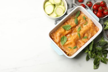 Pişirme kabında leziz vejetaryen lazanya ve beyaz masada malzemeler, düz yatak. Metin için boşluk