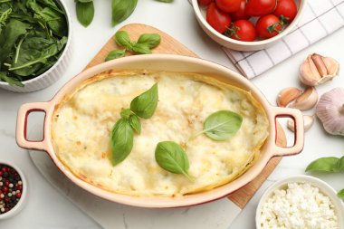 Lezzetli vejetaryen lazanyası ve beyaz mermer masa üzerindeki malzemeler.