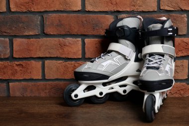 Tuğla duvarın yanındaki ahşap masada patenler. Metin için yer var.