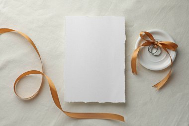 Düğün davetiyesi, gümüş yüzükler ve beyaz kumaşlı kurdele, düz yatış