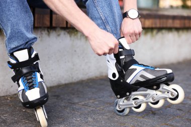 Genç adam patenleri dışarıda takıyor, yakın plan.