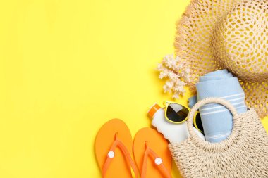 Plaj havlusuyla düz kompozisyon ve sarı arka planda diğer yaz aksesuarları. Metin için boşluk