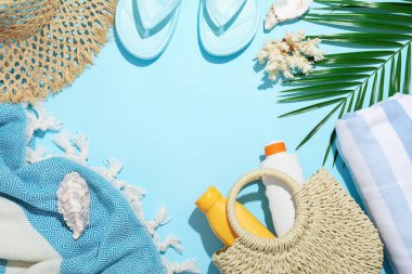 Plaj aksesuarları, deniz kabukları ve açık mavi arka planda palmiye yaprağı. Metin için boşluk