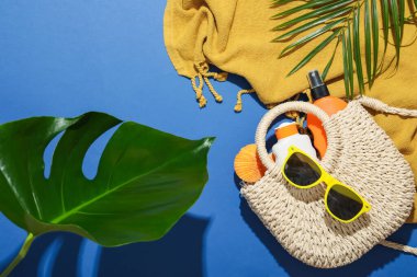 Plaj aksesuarları ve mavi arka planda palmiye yaprakları, düz yatış