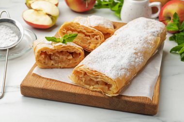 Beyaz mermer masada pudra şekeri, nane ve meyveli elmalı turtalar, yakın plan.