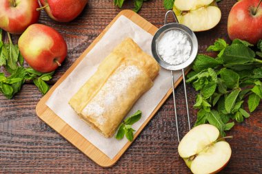 Lezzetli elmalı turta, pudra şekeri, nane ve ahşap masa üzerinde meyve, düz yatıyordu.