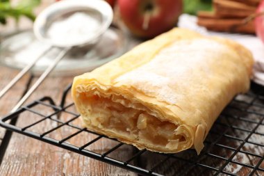 Ahşap masada pudra şekerli elmalı turta, yakın plan.