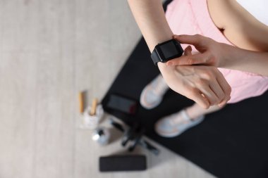 Kadın içeride, görüş alanının üstünde antrenman sırasında spor takip cihazını kontrol ediyor. Metin için boşluk