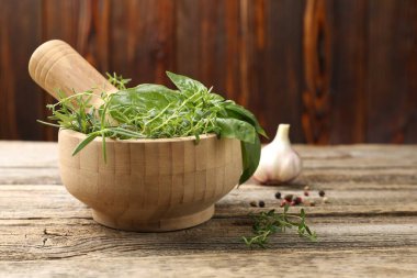 Kabuklu havan, ahşap masada farklı aromatik otlar ve baharatlar, yakın plan. Metin için boşluk