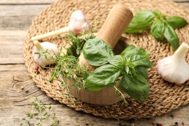 Kabuklu havan, farklı aromatik otlar ve baharatlar ahşap masada, yakın plan.